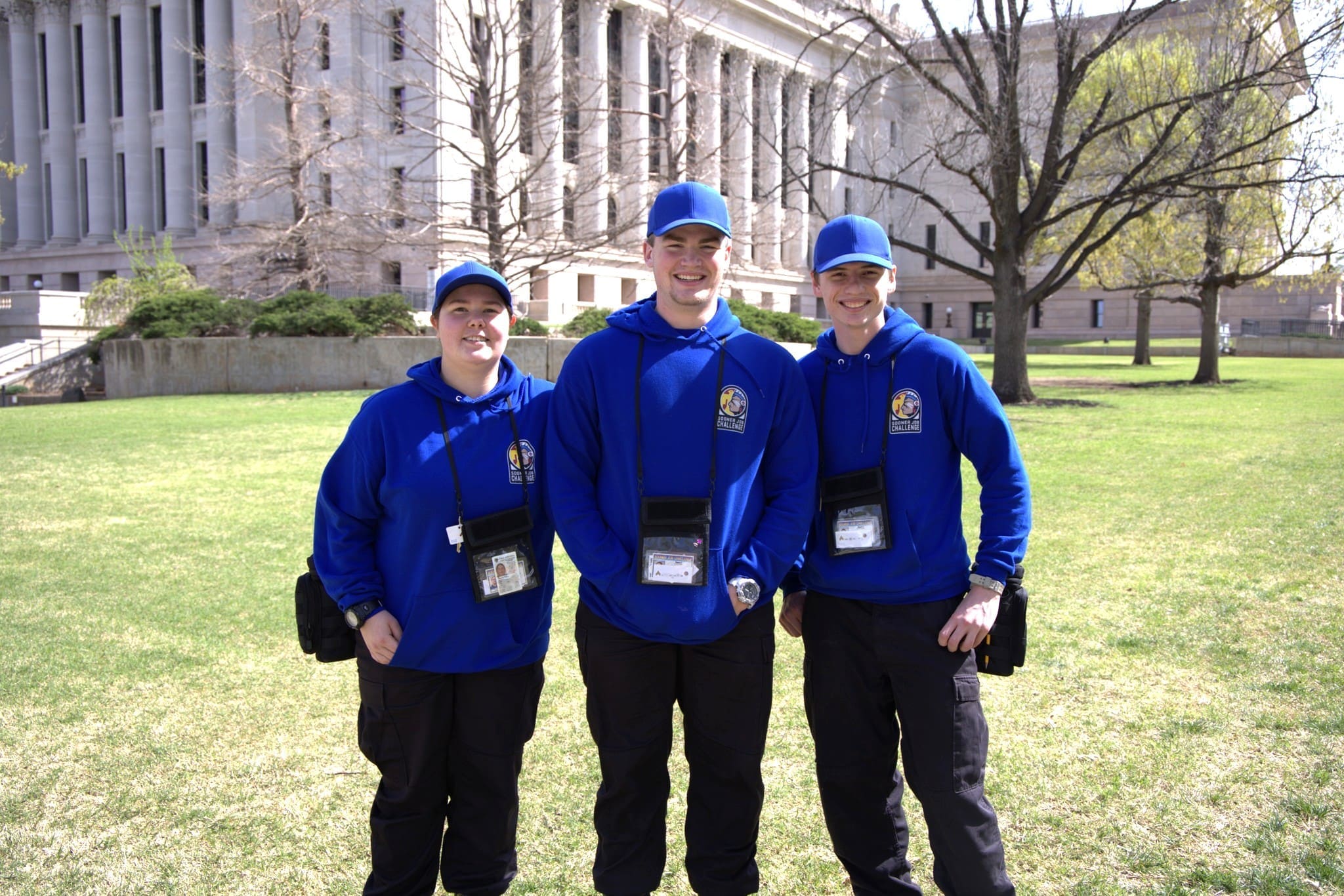 Three Sooner Job Challenge associates in blue uniforms standing outside the State Capitol