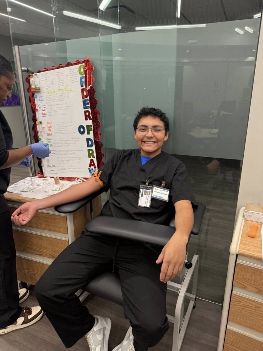 Associate smiles as he waits for his blood to be drawn.