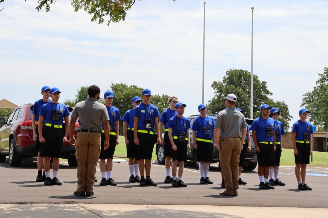 Cycle 2 Associates stand in formation outside. RA's stand in front of Associates, facing away from camera. Everyone is outside.