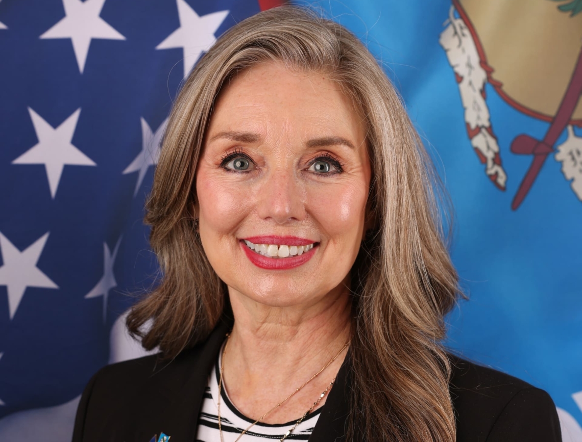 Headshot of Rosemary Masters with US and OK flags behind her