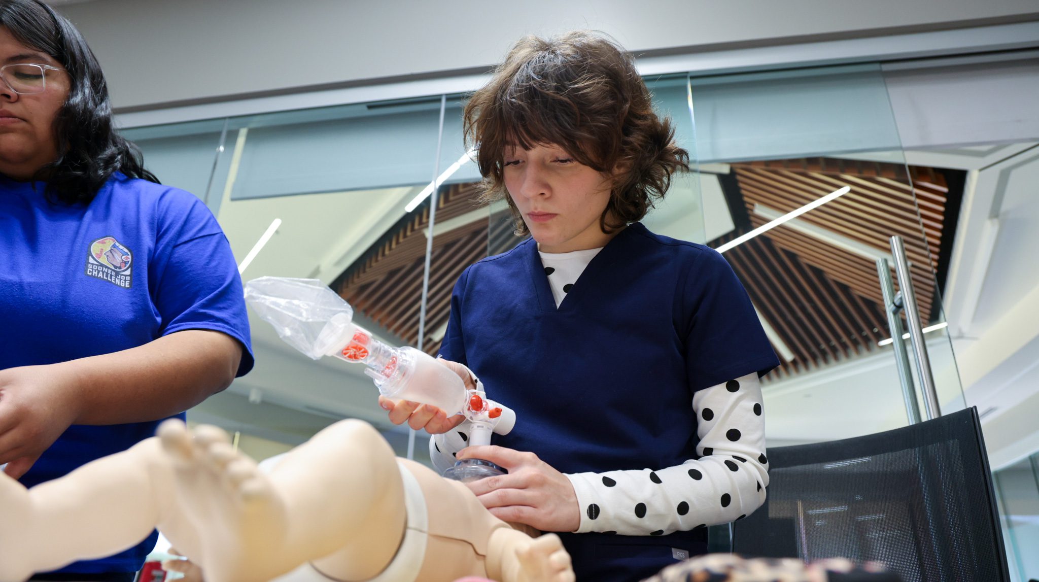 Female student learning to do CPR on an infant CPR doll.