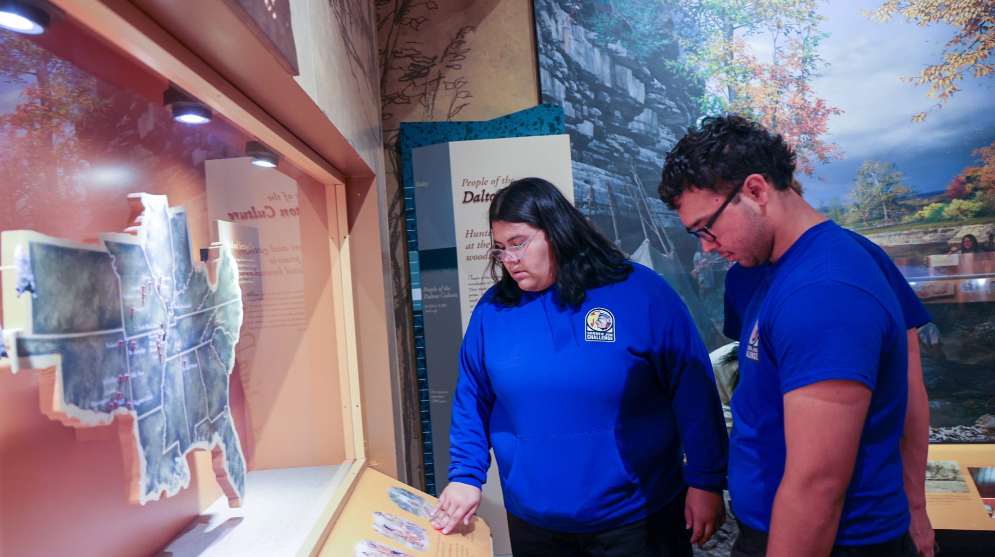 A male and female student looking at a native american display map in a glass case.