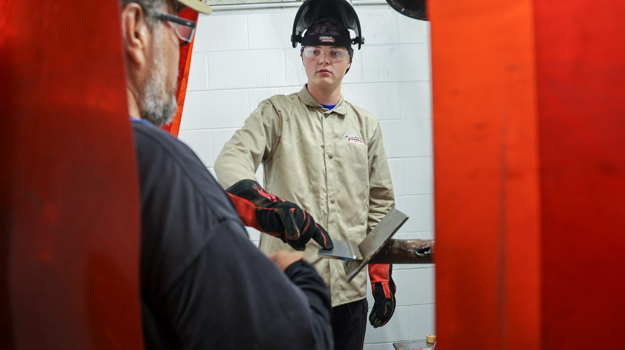 Male welding student showing his welding instructor his completed weld.