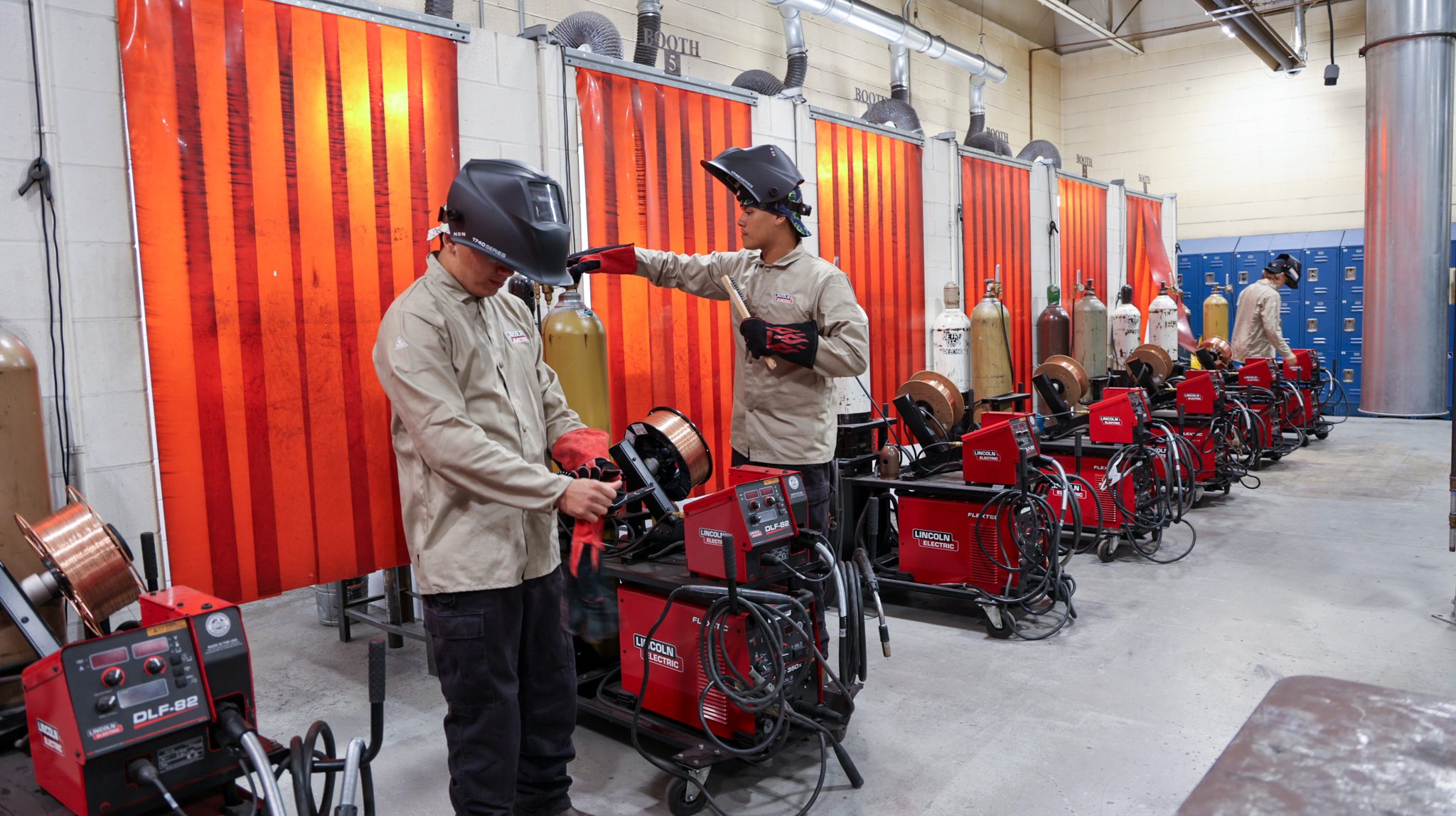 Two male welding students getting their equipment ready. One is turning on his gas bottle.