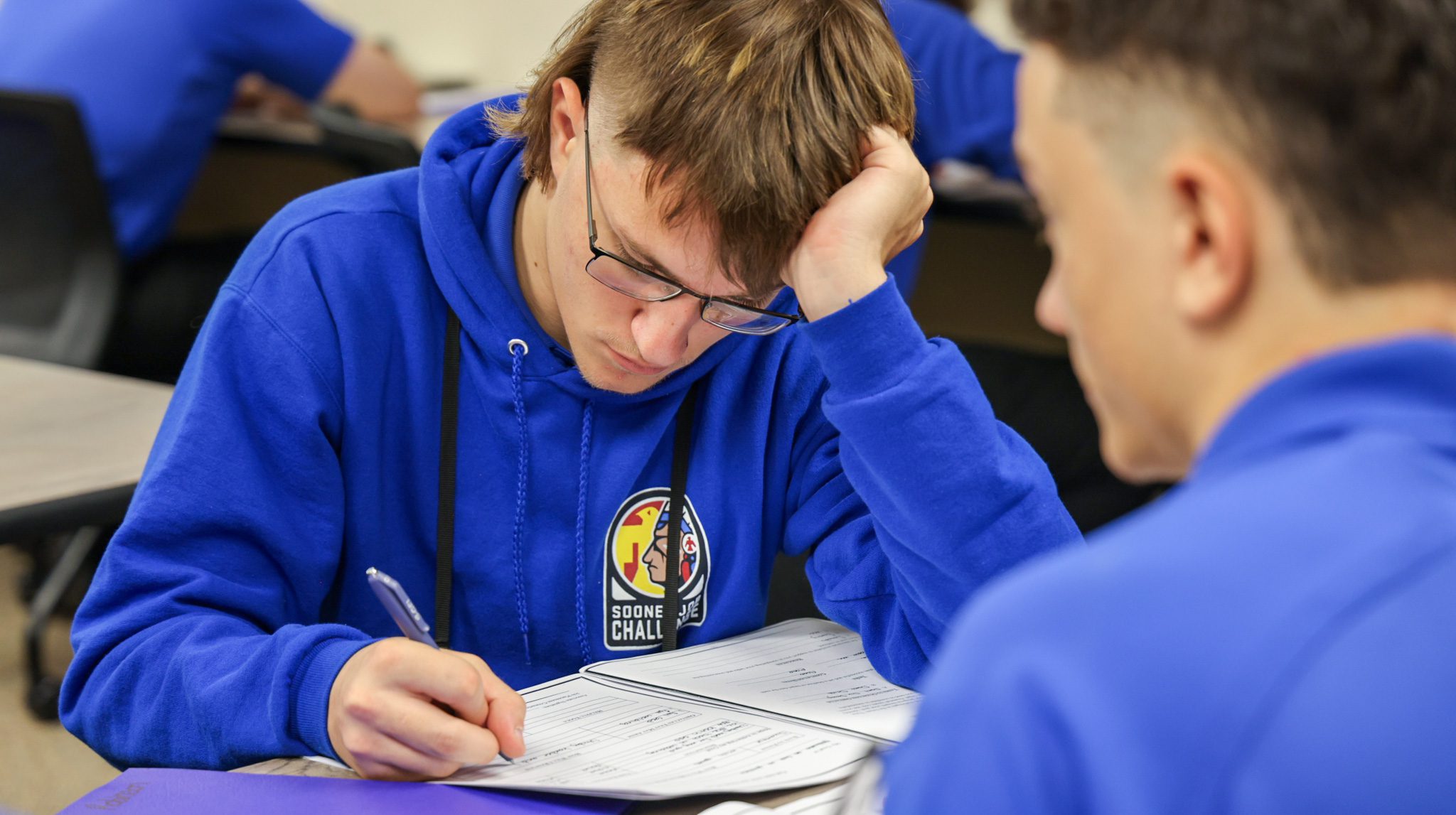 Male student writing in a booklet.