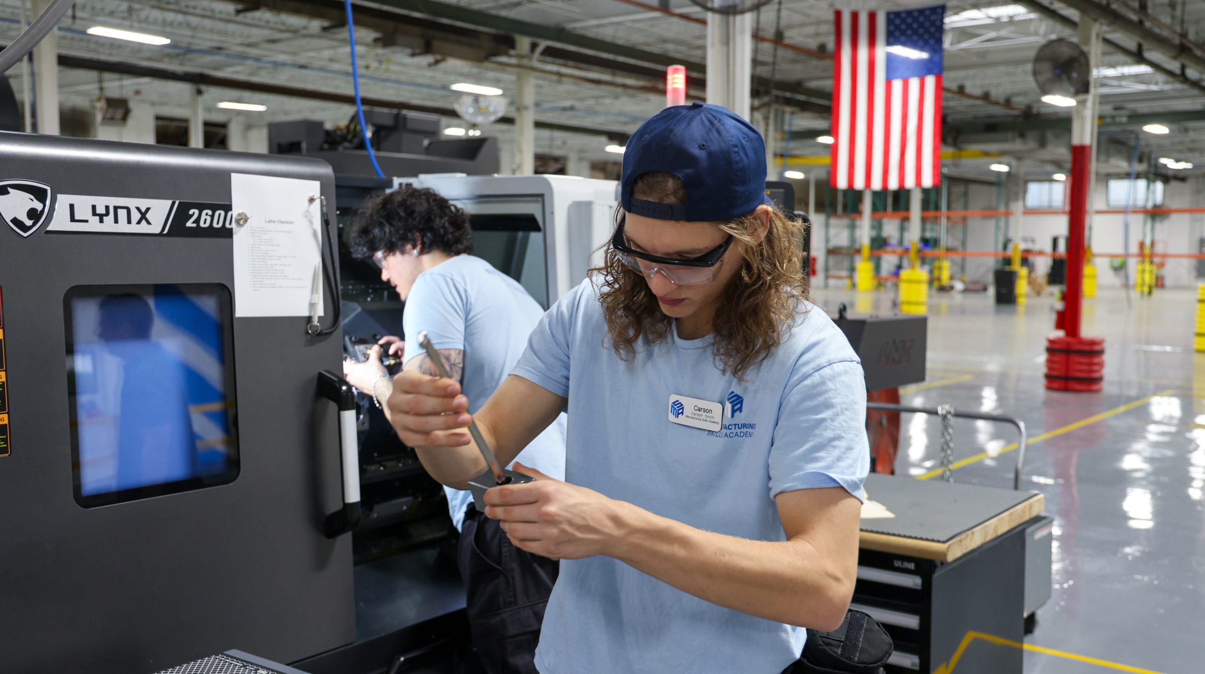 Male student using a tool to adjust a CNC tool.