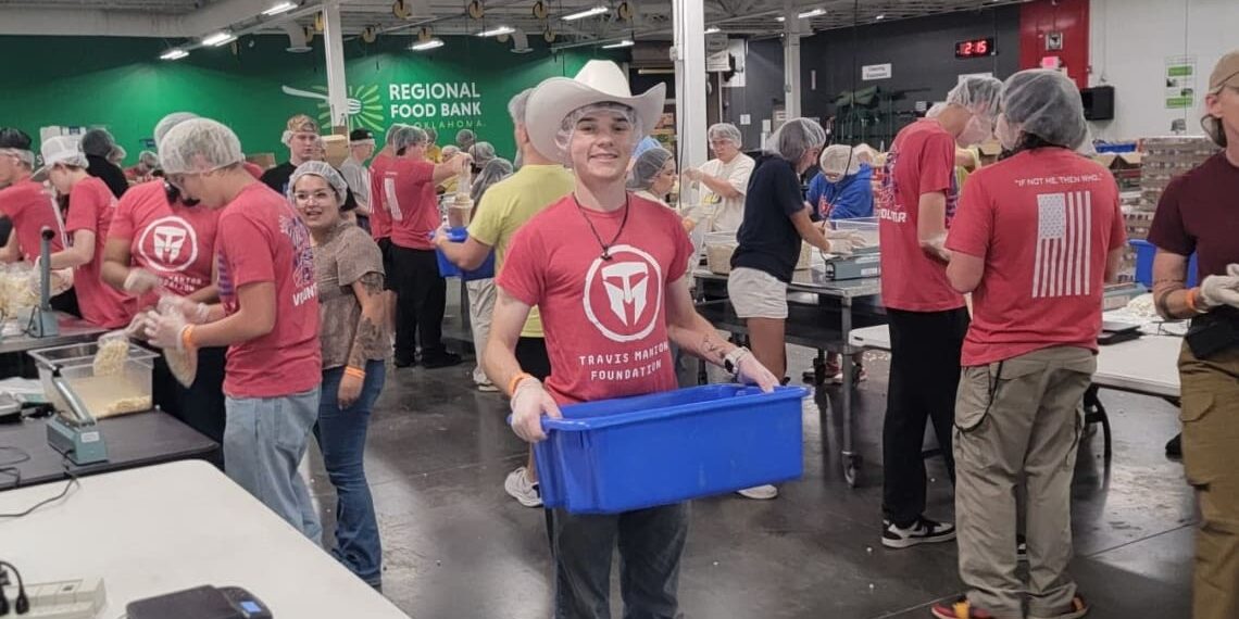 Associates are volunteering at Regional Food bank, completing various tasks around the room. In the center of an image, one Associate, who is wearing a hairnet and a cowboy hat, smiles while holding a blue tub.