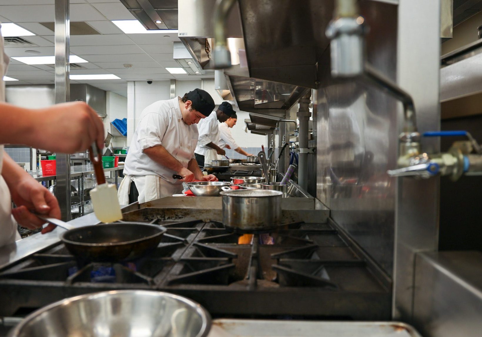 Male students at several gas stoves cooking.