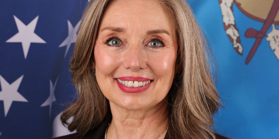Headshot of Rosemary Masters with US and OK flags behind her