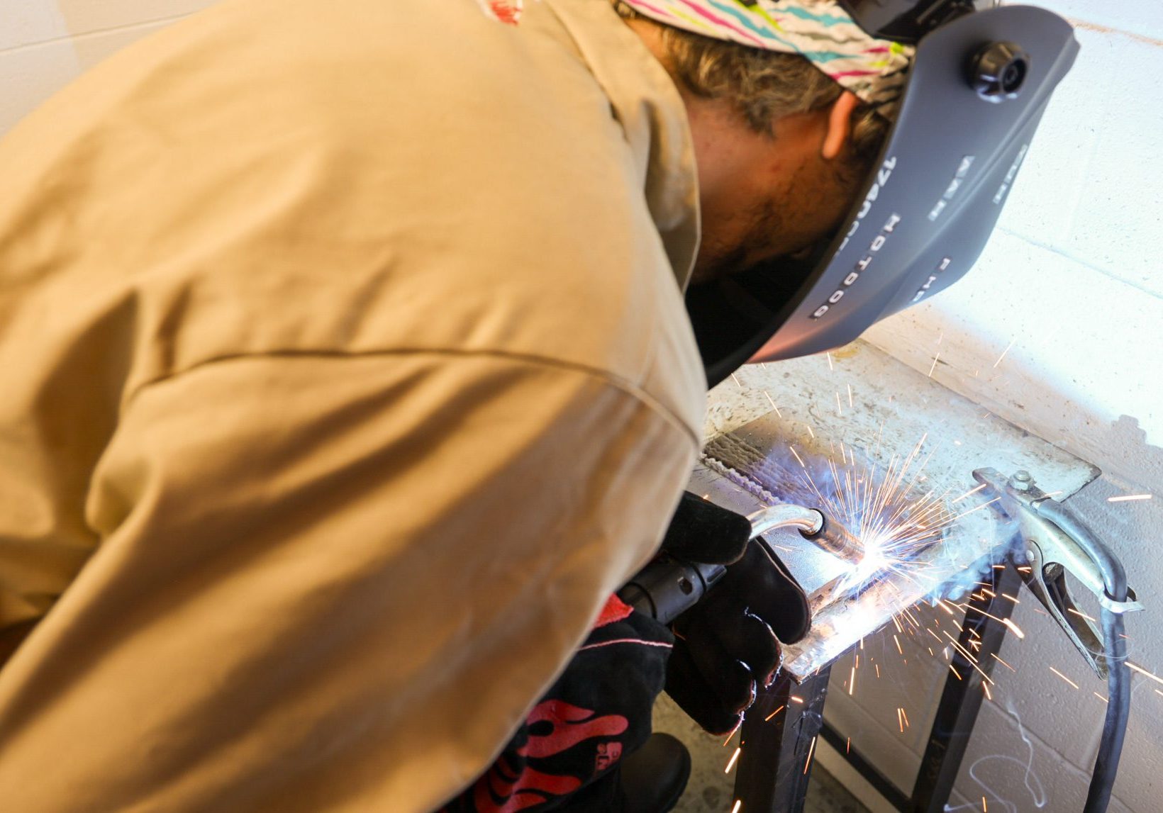 Welder welding a small metal plate.